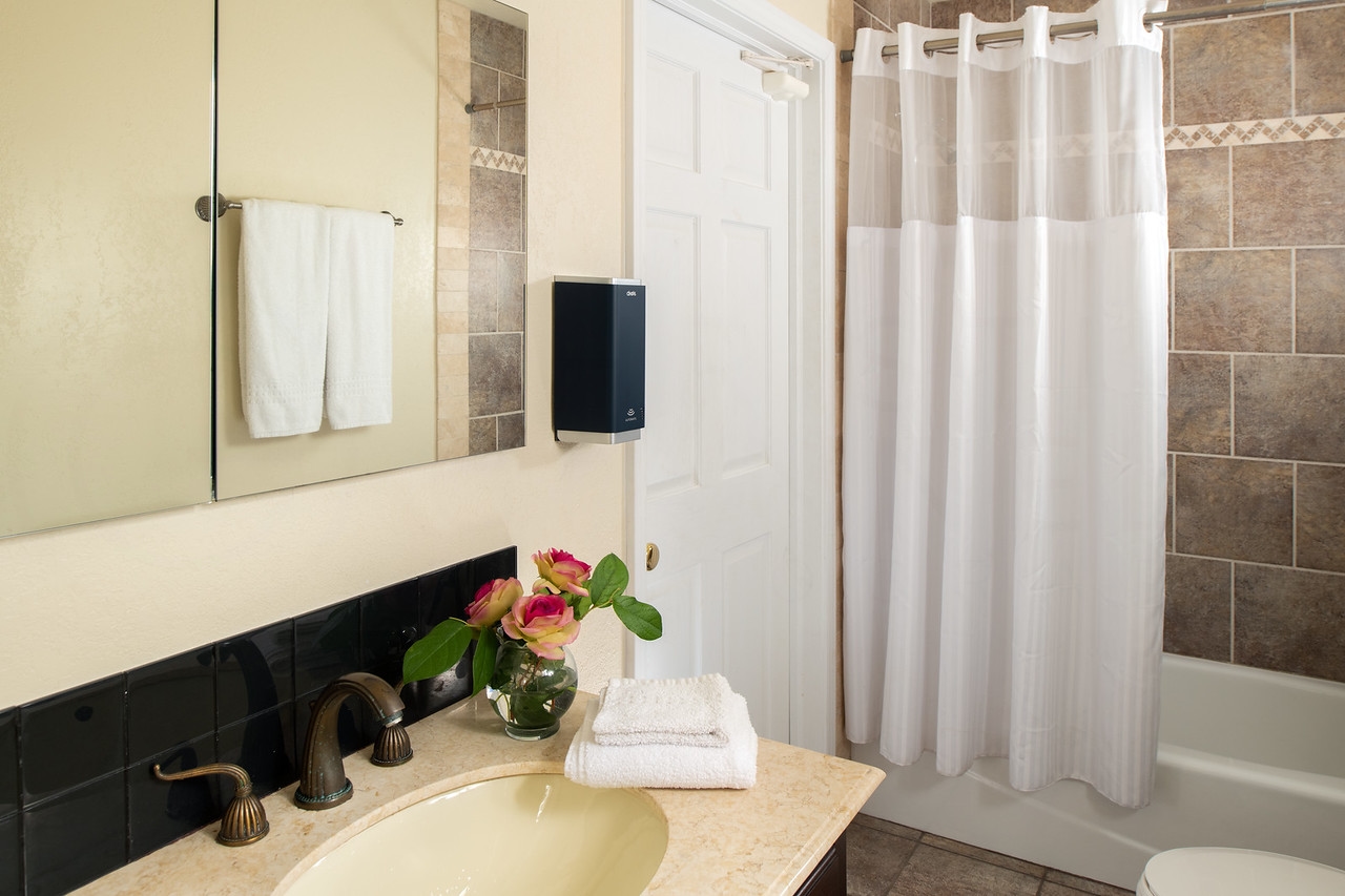 Sink with vanity, plush white towels, and tiled shower