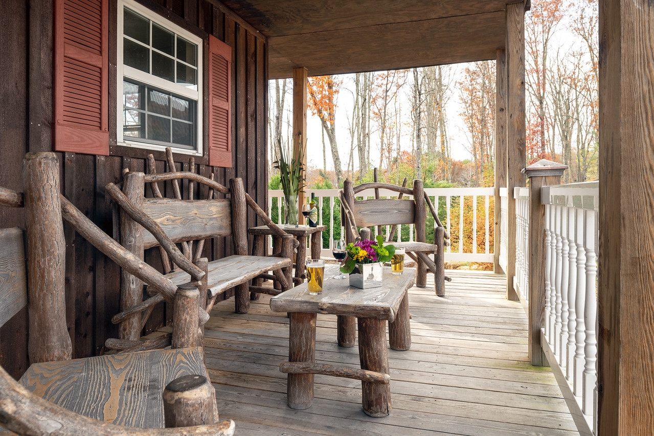 Front porch deck with rustic wooden chairs, bench, and coffee table