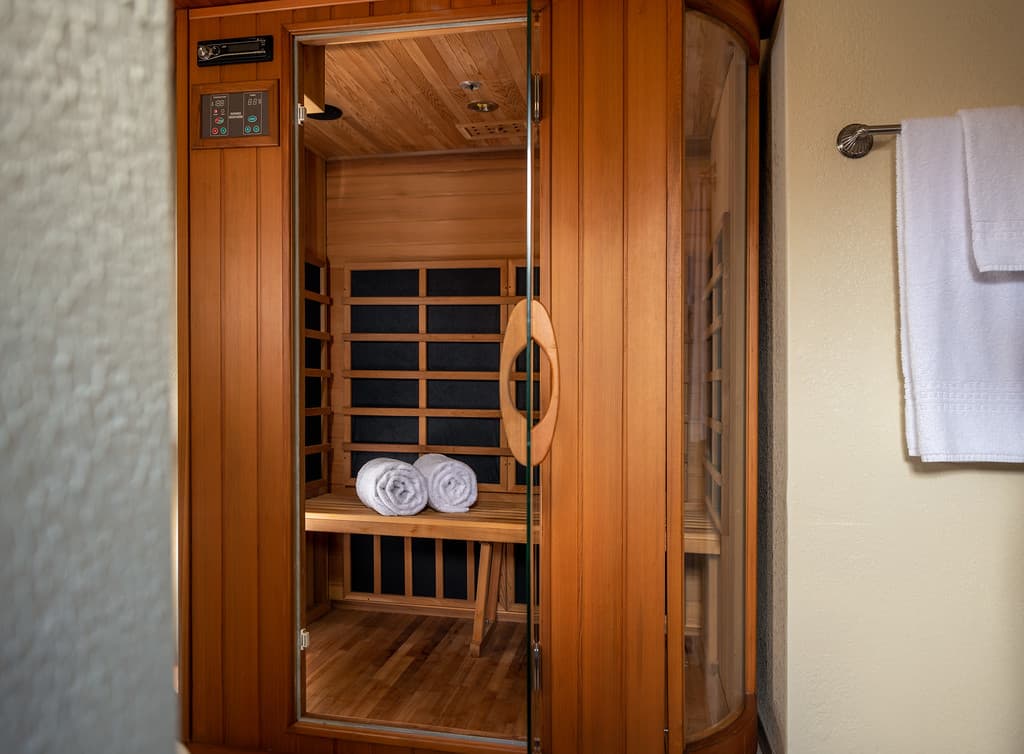 Doorway into dry FIR Sauna room with plush white towels hanging on a rack nearby on wall