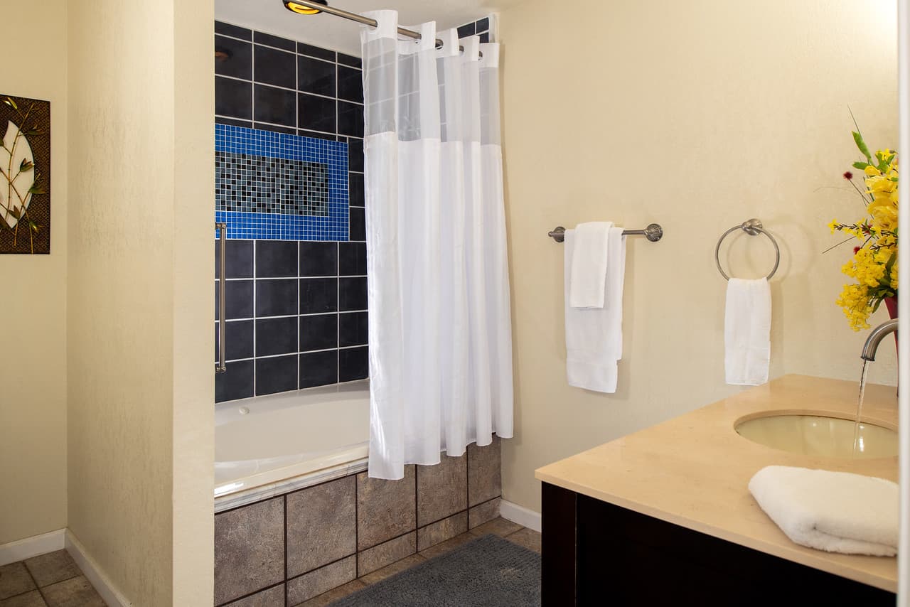 Downstairs bathroom with tiled shower and vanity with sink, plush white towels hanging on the wall