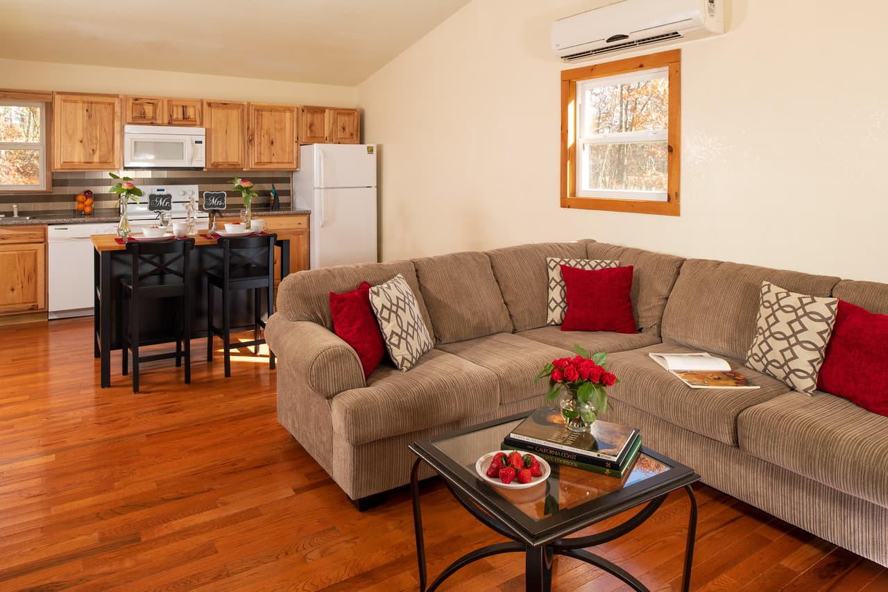 Comfy beige sectional couch, hardwood floors, and well-equipped kitchen in background