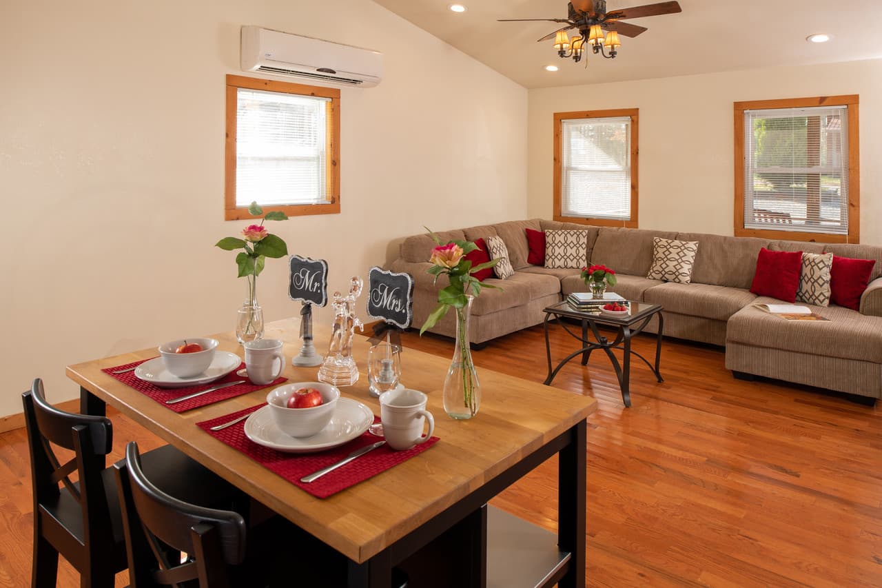 Table for two set for breakfast with sectional couch in the background, hardwood floor, and ceiling fan