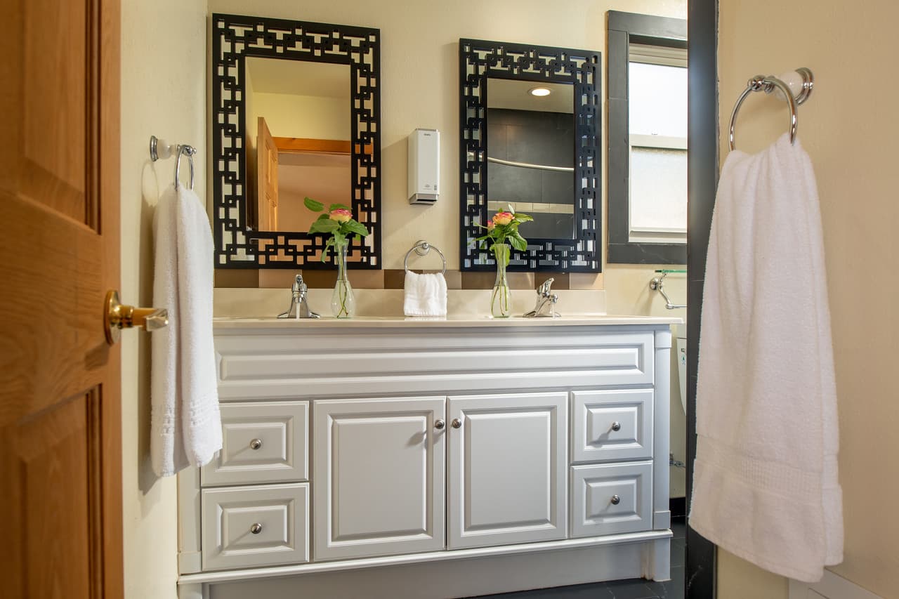 Doorway to bathroom showing white wooden vanity with double sinks