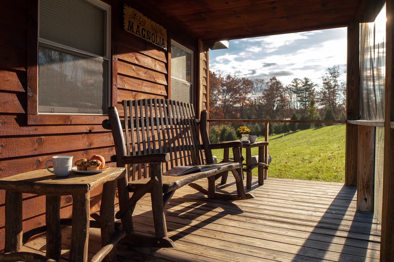 Front porch deck with rustic wood furniture and view of lawn and trees