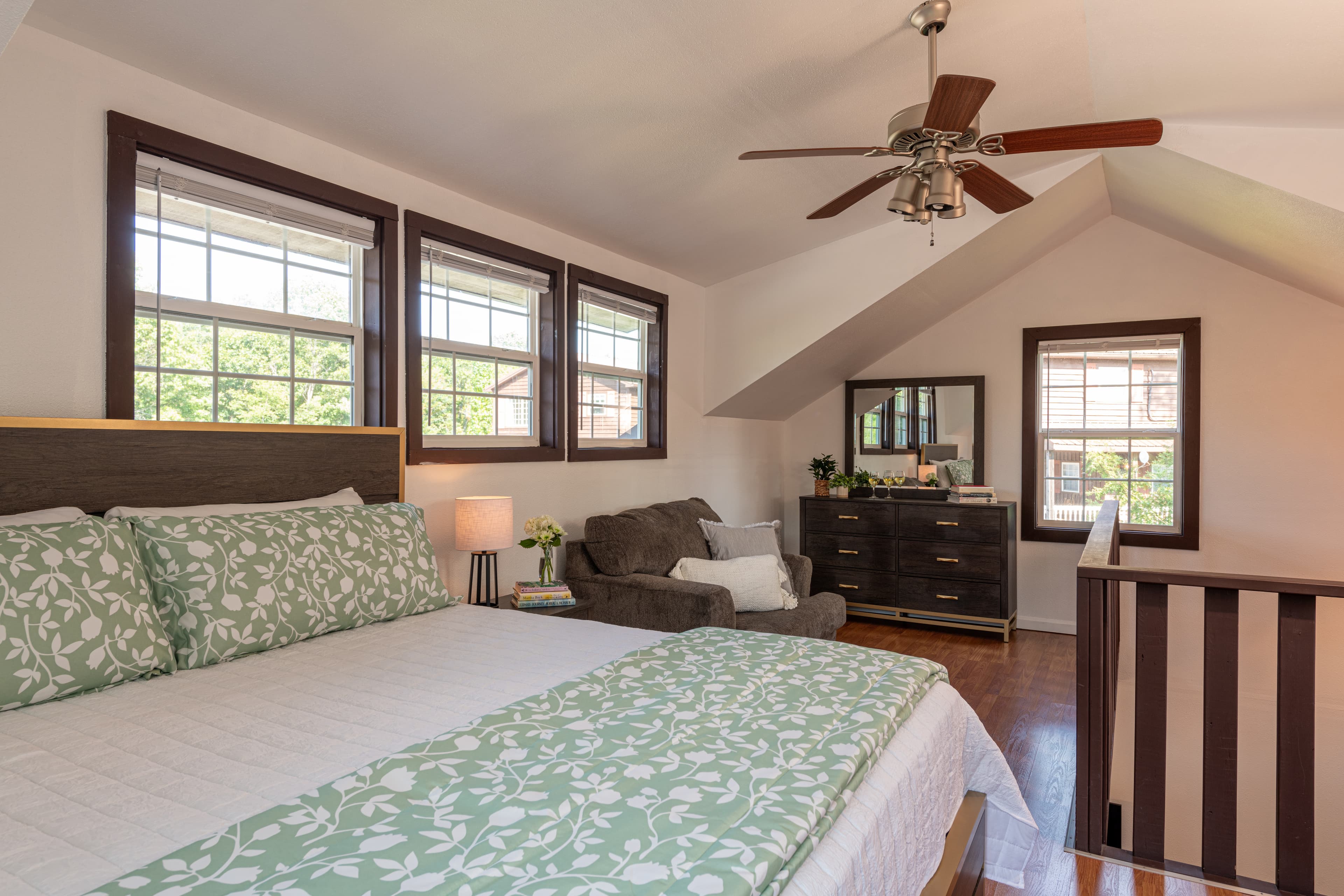 Upstairs dining area with table and chairs for four, matching side table, sunny windows, and hardwood floor