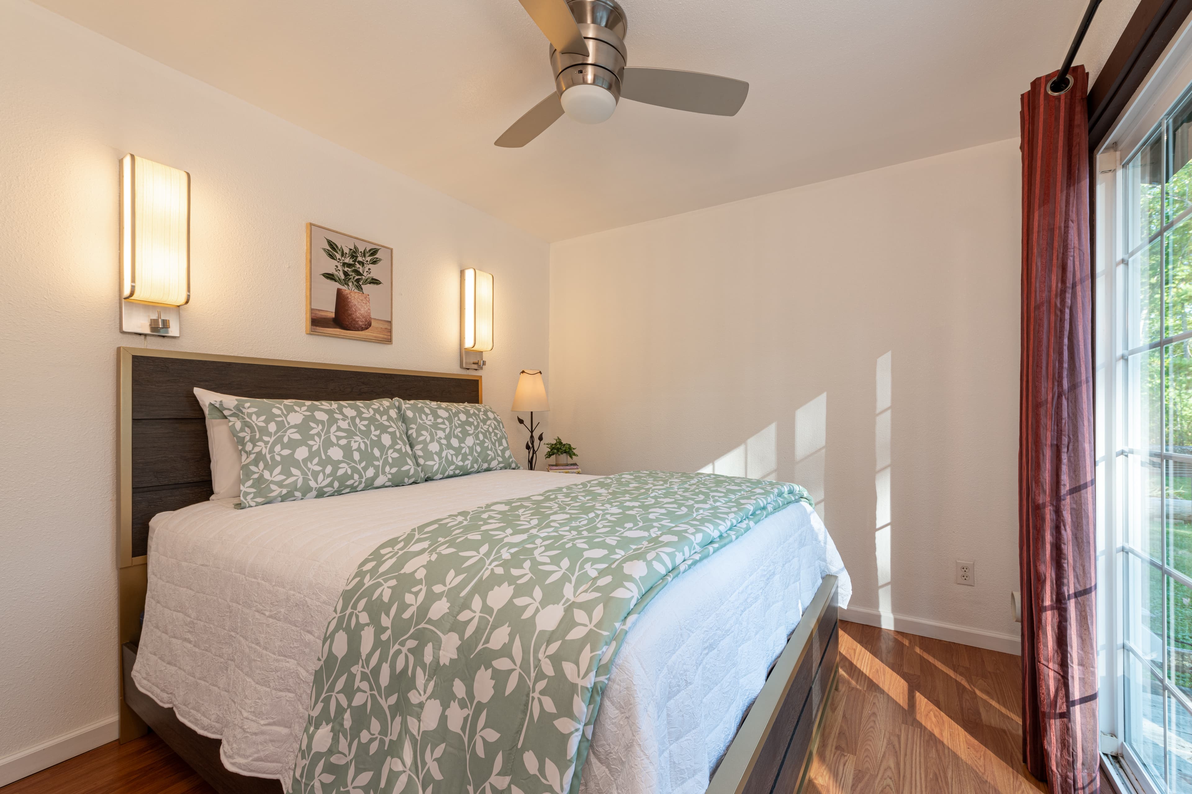 Second bedroom with black wooden platform bed, white sheets, red blanket & red throw pillows