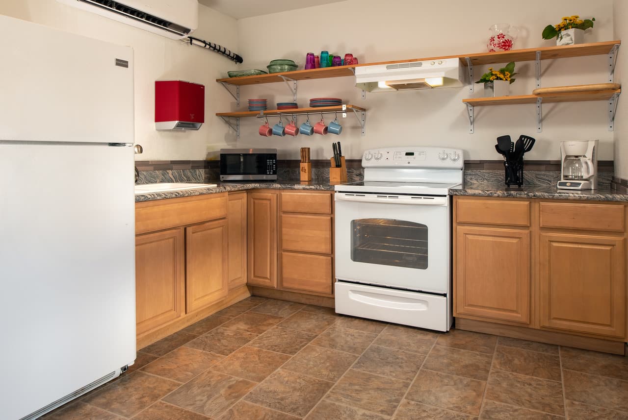 Fully equipped kitchen with refrigerator, stove, cabinets, and open shelves (has dining area - not shown)