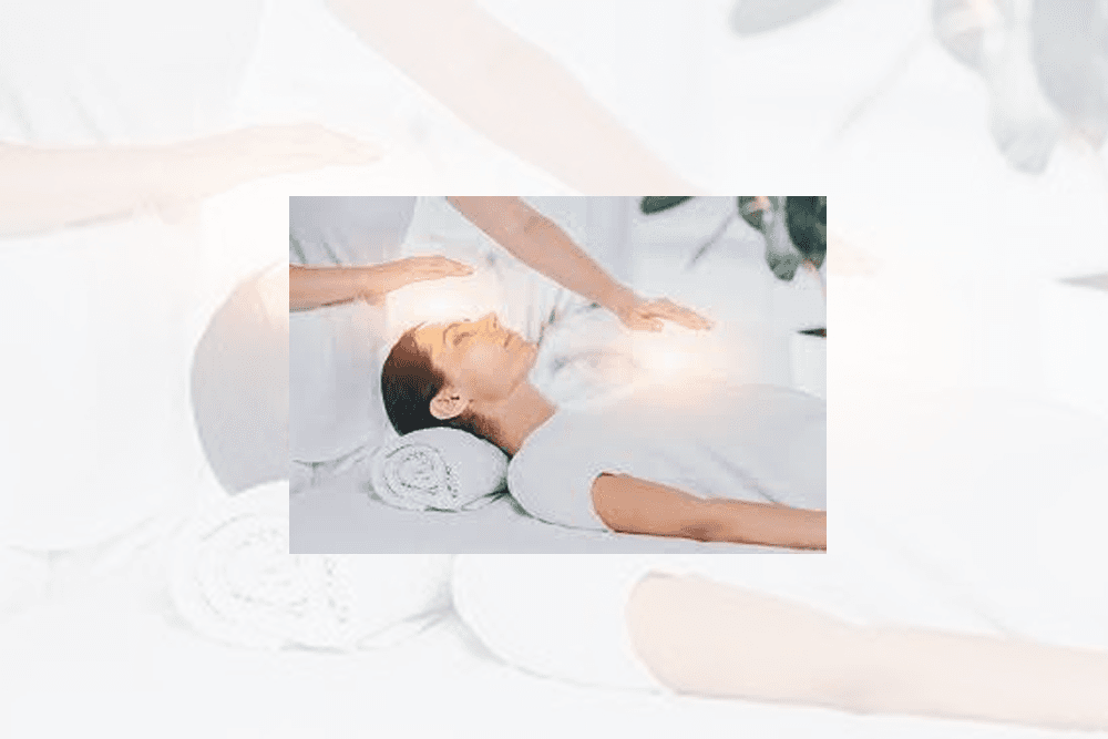 Woman laying on table with aura showing with practitioners hands above her body