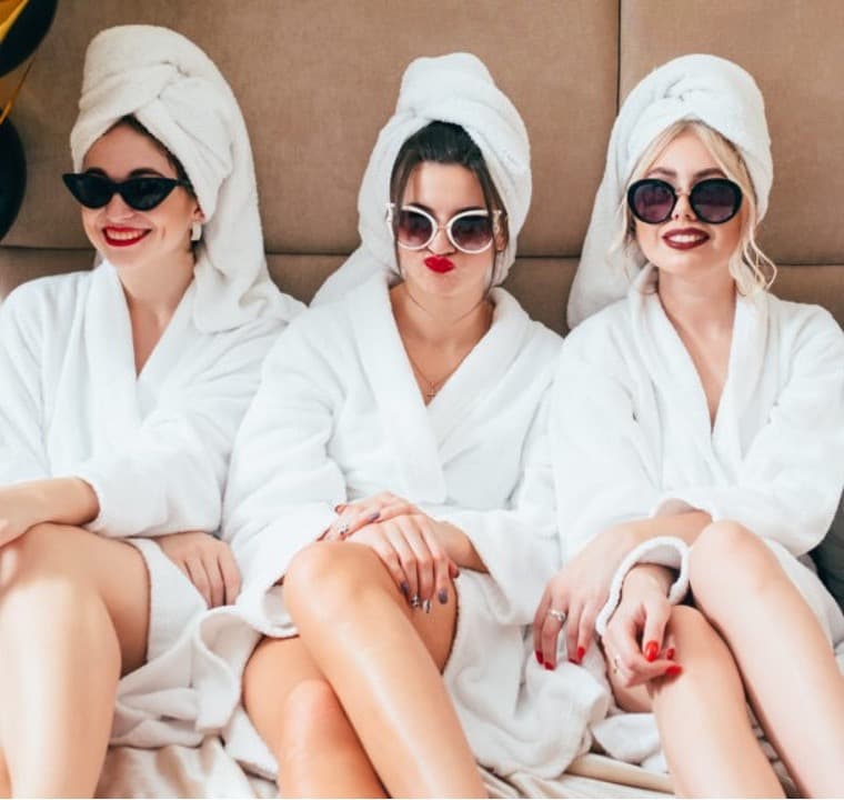 3 women in white robes, sungless, red lipstic, hair turbins having fun