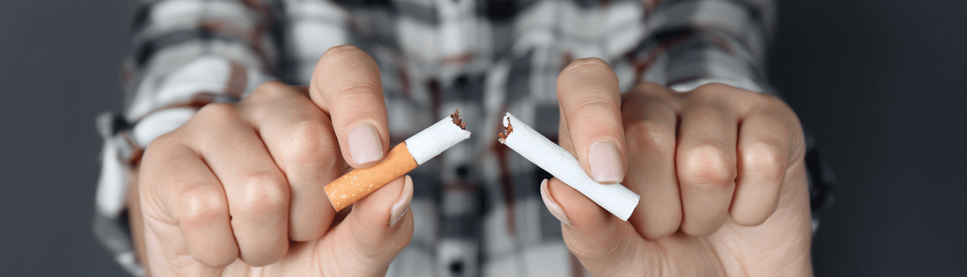 Woman in blue plaid shirt holding broken cigarette in front of her