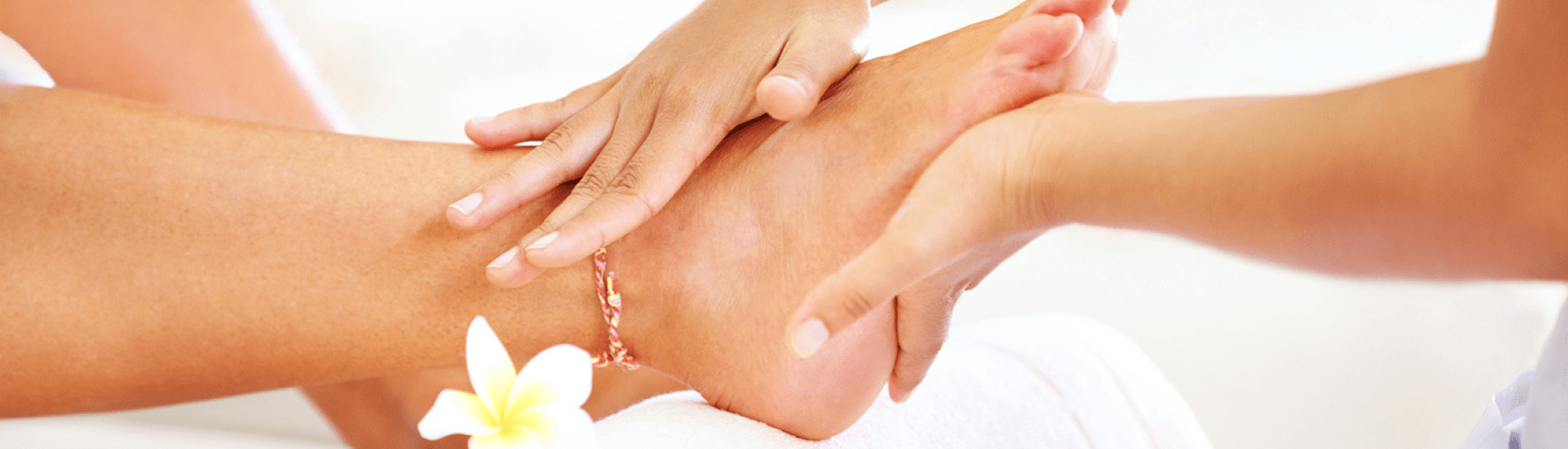 Hands giving pedicure with flowers in background