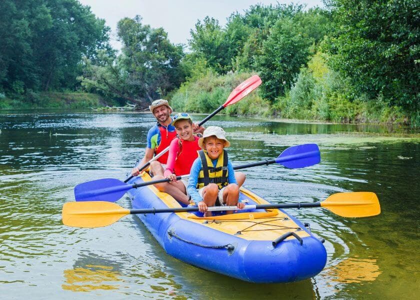 A family joyfully kayaks on a tranquil river surrounded by lush greenery. A family joyfully kayaks on a tranquil river surrounded by lush greenery.