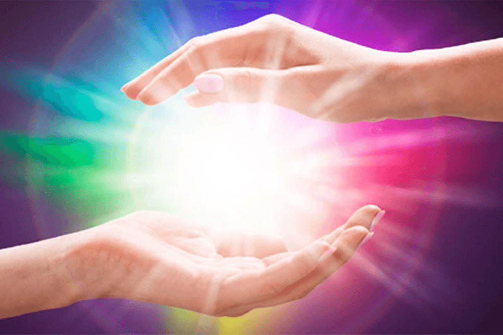 Multi color background with 2 hands holding a ball of visable energy